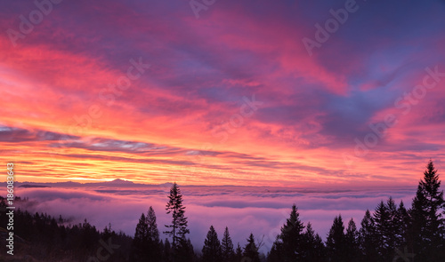 Colorful sunrise with low dense clouds covering the city of Vancouver. Mount Baker in the distance