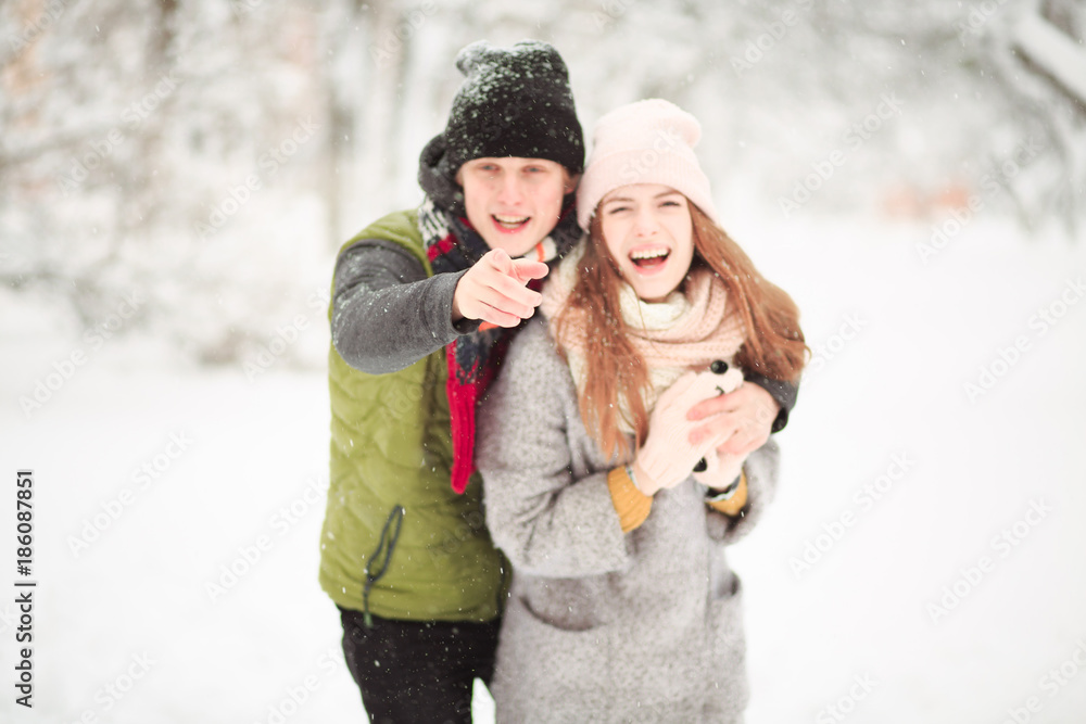 Obraz premium Romantic couple walking in the street. A boys sees something funny and shows his girlfriend.