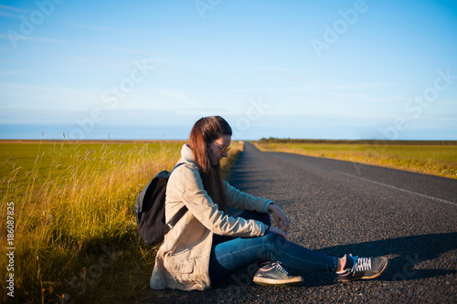 Young woman tourist sits on the road. © Ulia Koltyrina