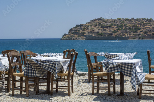 Many tables and chair of the street restaurant in Greece in the windy day