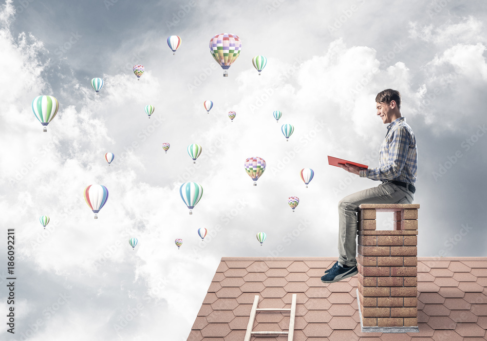 Handsome student guy reading book and aerostats flying in air Handsome student guy reading book and aerostats flying in air