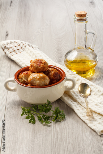 Fried meat cutlets in ceramic soup bowl, branch of fresh parsley, bottle with sunflower oil and kitchen towel with spoon