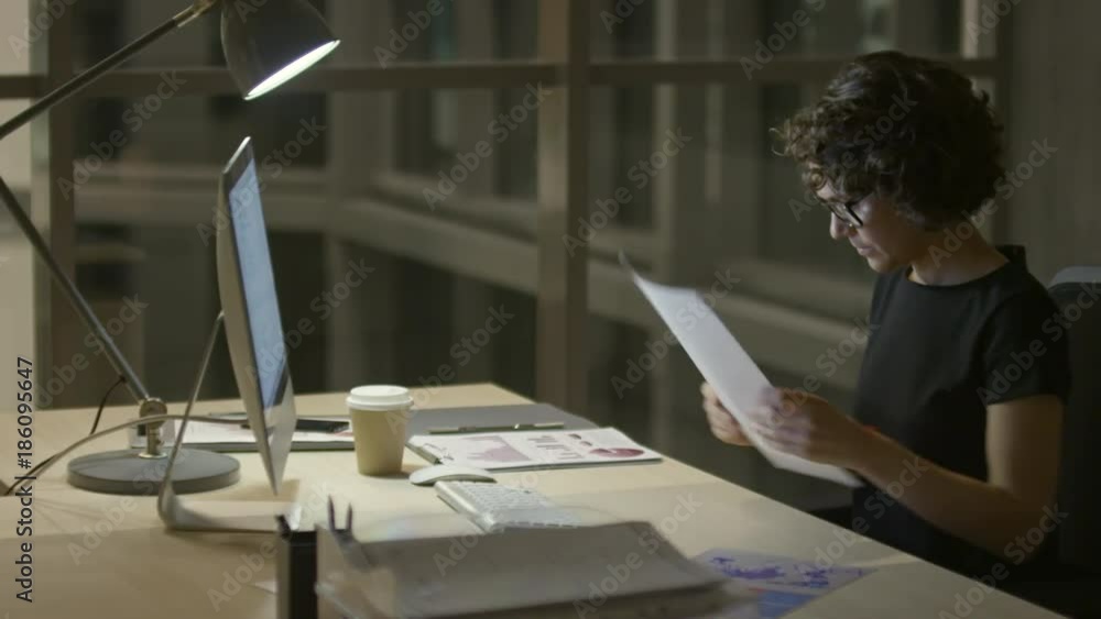 Businesswoman typing on computer and writing on document in the office at night
