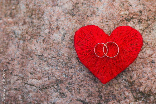 love heart and two golden rings on stone  granite background .card with love. emotions and feelings concept. Selective focus. Copy space