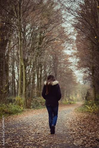 Lonely girl walking down a path in fall