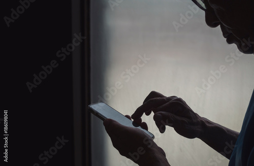 Vintage filtered on silhouette of male elderly using smart phone