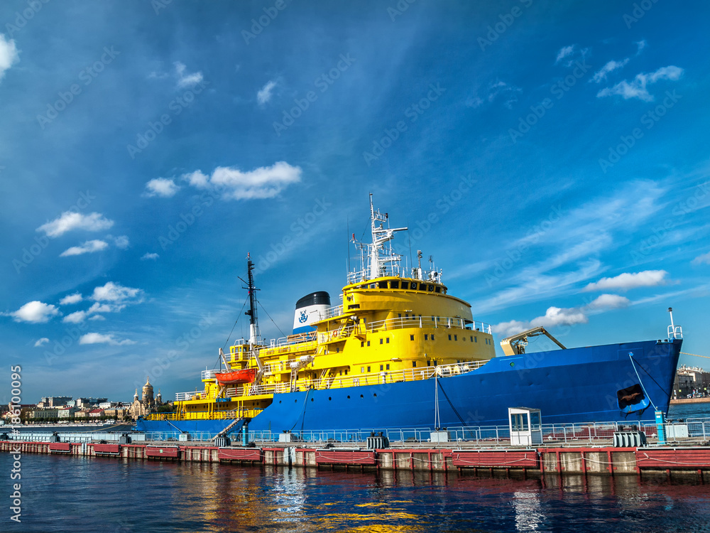 Diesel icebreaker of yellow-blue color on the pier near the embankment in the city of St. Petersburg in Russia