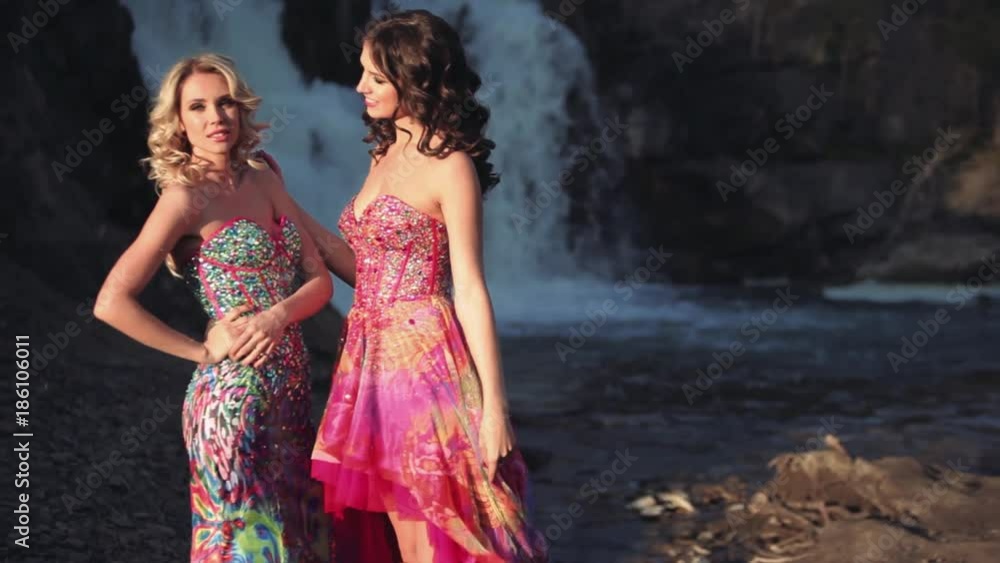 Two beautiful sexy girls posing against a waterfall background Two beautiful sexy girls posing against a waterfall background