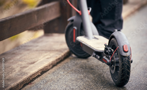 Electric scooter stands on a bridge in the street.