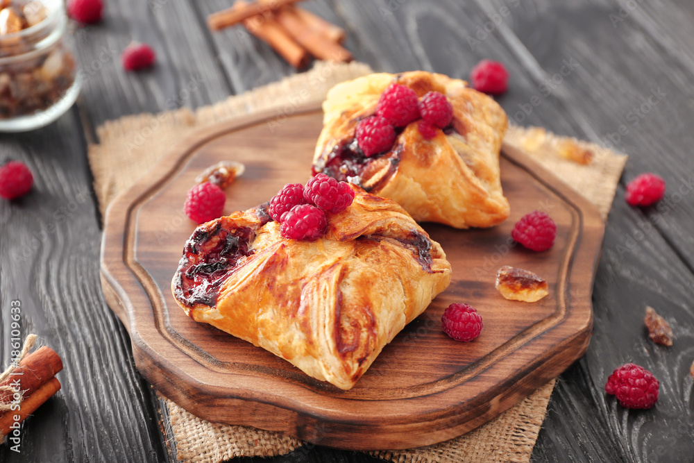 Board with delicious puff pastries and raspberries on table Board with delicious puff pastries and raspberries on table