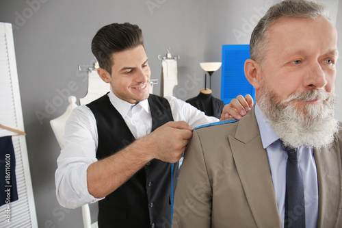 Tailor taking client's meas...