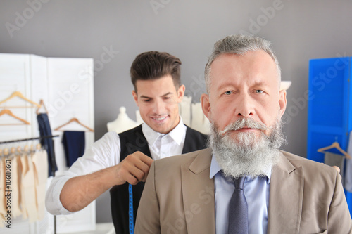Tailor taking client's meas...