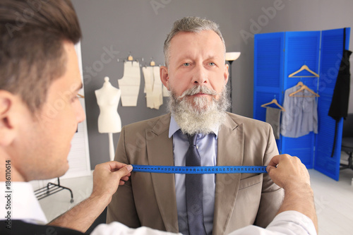 Tailor taking client's meas...