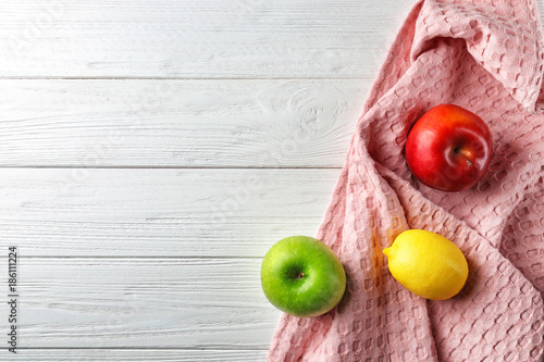 Clean kitchen towel and fruits on white wooden table, top view