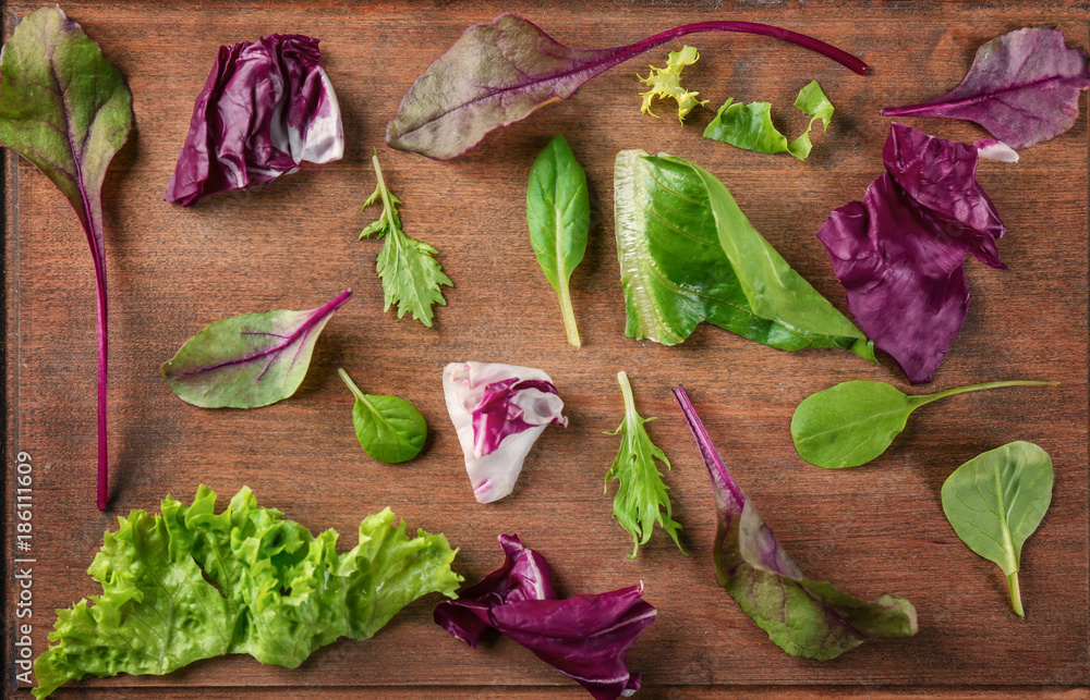 Leaves of different salads on wooden background, top view Leaves of different salads on wooden background, top view