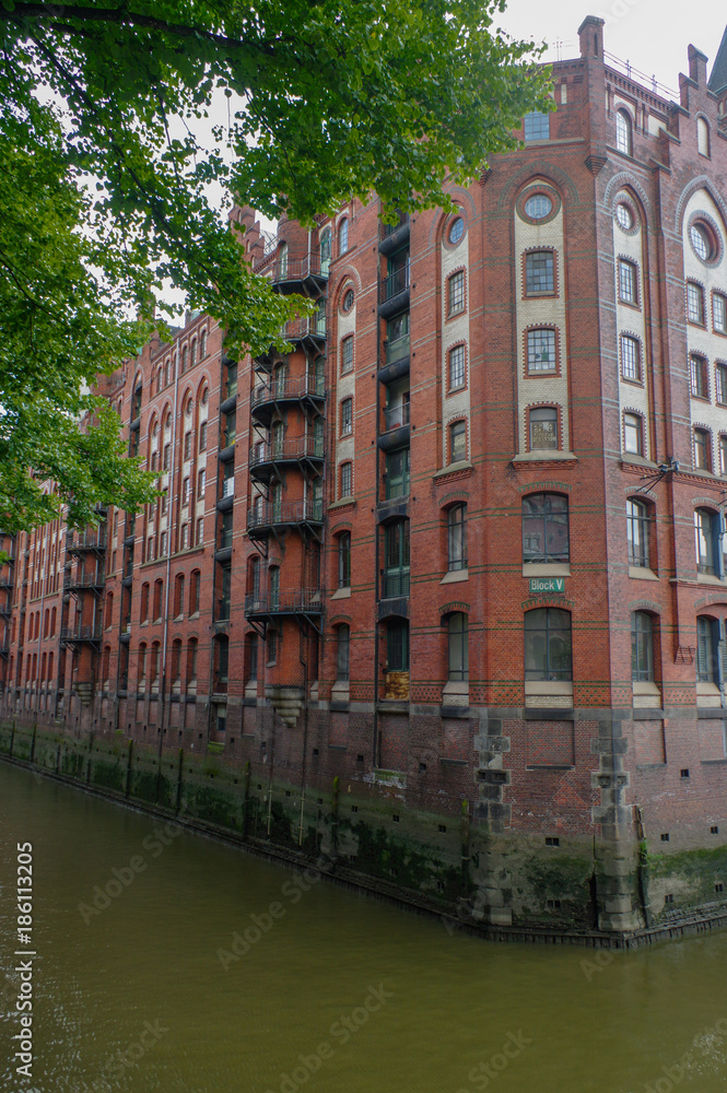 HAMBURG, GERMANY - JULY 18, 2015: ferry on the canal of Historic Speicherstadt houses and bridges at evening with amaising skyview over warehouses, famous place Elbe river.