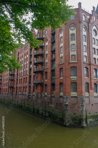 HAMBURG, GERMANY - JULY 18, 2015: ferry on the canal of Historic Speicherstadt houses and bridges at evening with amaising skyview over warehouses, famous place Elbe river. © evolutionnow
