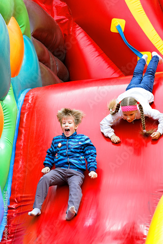 Brother and sister have fun in the park on an inflatable slide