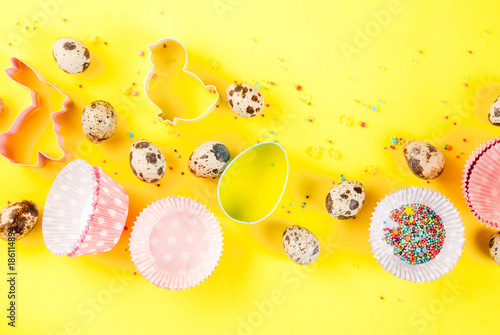Sweet baking concept for Easter  cooking background with baking - with a rolling pin  whisk for whipping  cookie cutters  quail eggs  sugar sprinkling. Bright yellow background  top view copy space