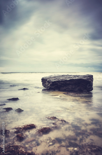 Rock on a beach, peaceful natural background, color toned picture, selective focus.