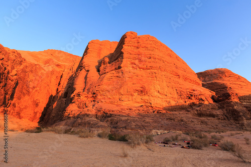 Sleeping outdoors on the ground with red colored rocks in the Wadi rum desert in Jordan at early-morning on the background