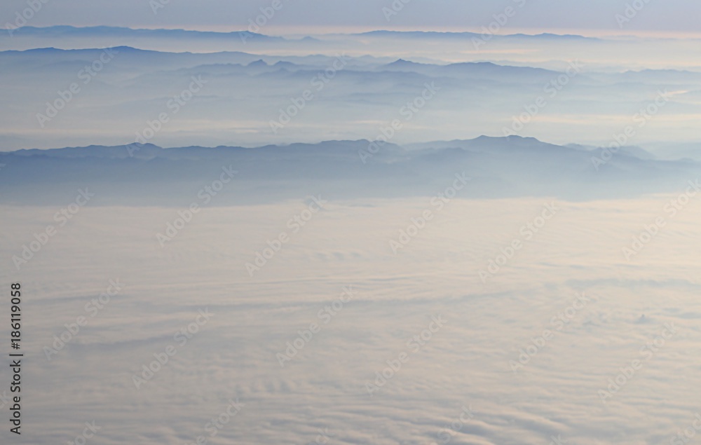 White clouds against the background of mountains looking from the plane.