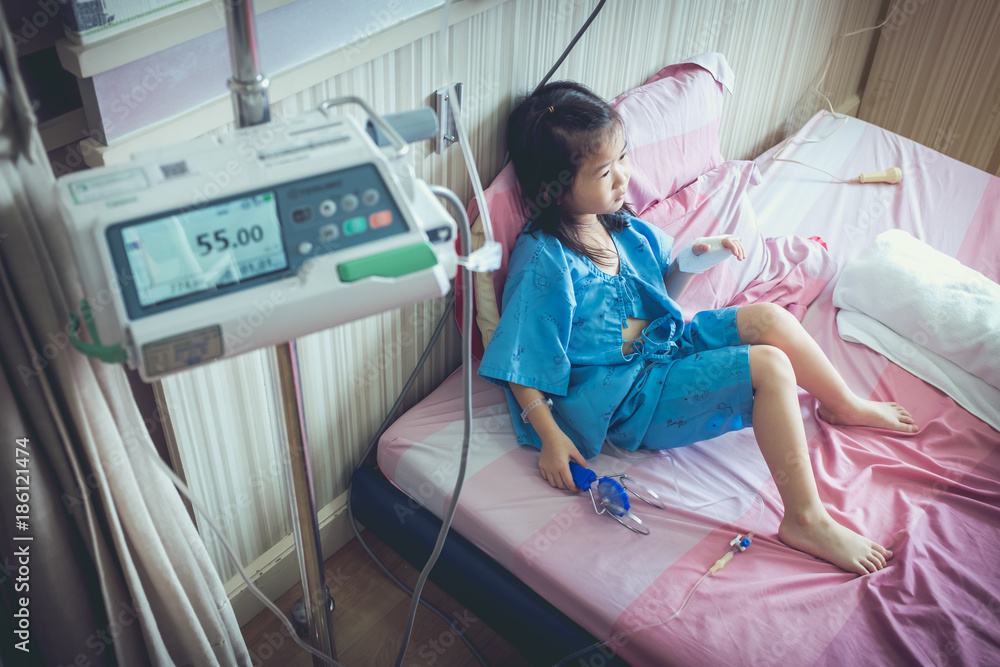 Illness asian child admitted with saline iv drip on hand.