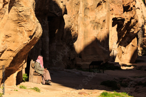 Man stitting in a small passage between the steep rocks at Little Petra in Siq al-Barid, Wadi Musa, Jordan