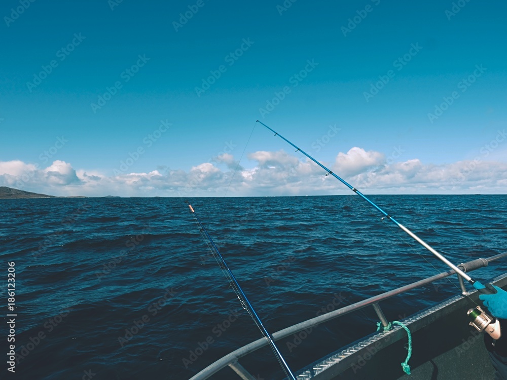 Sea fishing from steel fishing boat on open water. Rocky island et horizon.