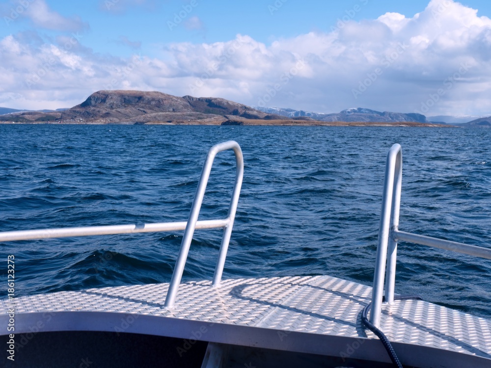 Sport boat sailing in blue mediterranean tranquil sea. Rocky island at horizon