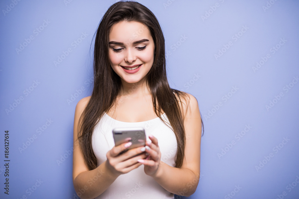 Closeup portrait smiling or laughing young freelancer woman looking at phone seeing good news or photos with nice emotion on her face isolated wall background. Closeup portrait smiling or laughing young freelancer woman looking at phone seeing good news or photos with nice emotion on her face isolated wall background.