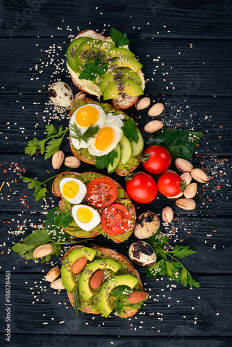 Fototapeta Naklejka Na Ścianę i Meble -  A set of avocado sandwiches, cherry tomatoes and quail eggs and chia seeds. On a wooden background. Top view. Free space for your text.