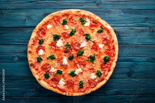 Neapolitan Pizza. Spinach, gorgonzola cheese, sausage salami. On a wooden background. Top view.