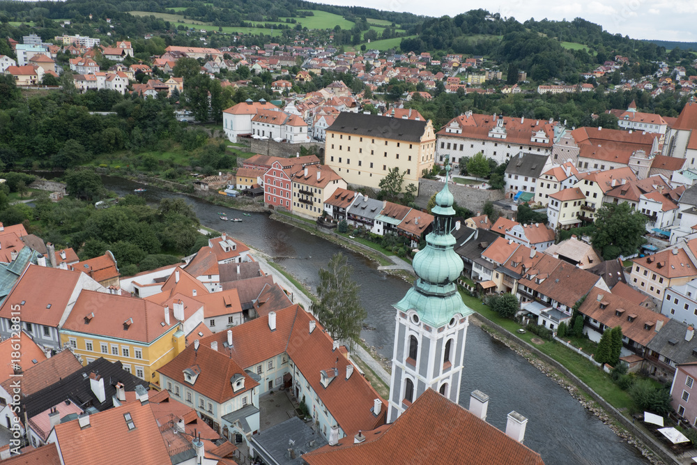 View of the charming medieval town, Cesky Krumlov, from the castle tower. Looking over the town from high up, Church of St Jost overlooking the Vltava River flowing through the town.