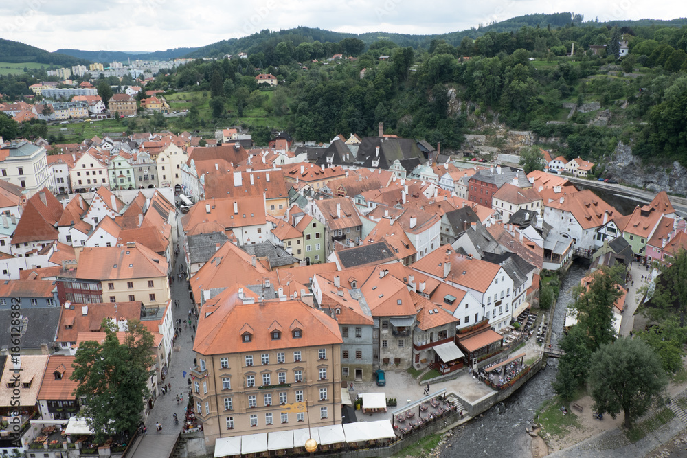 View of the charming medieval town, Cesky Krumlov, from the castle tower. People eating outside next to the Vltava River and walking down the street.