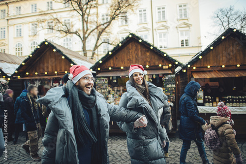 Happy couples on the city square decorated for a Christmas market