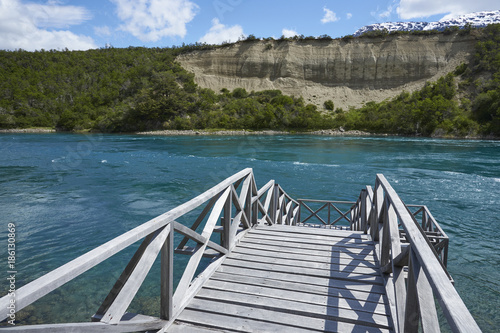 Wooden jetty jutting out into the blue glacial waters of the Rio Baker snaking through the lush vegetation of northern Patagonia in Chile. photo