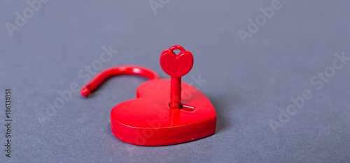 alla hjärtans dag symbolisk bild med rött öppet hjärtformat hänglås med nyckel mot grå bakgrund photo