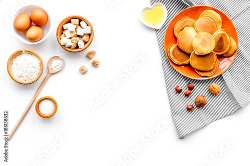 Cooking american pancakes. Ingredients, cakes, nuts and honey on white background top view copyspace photo