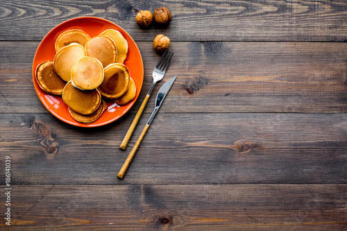 Pile of hot homemade pancakes on bright plate. Dark wooden background top view copyspace photo