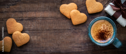 Beautiful Valentine's Day banner with copyspace. Romantic morning with cup of espresso coffee, heart shape cookies and a gift box on rustic wooden table