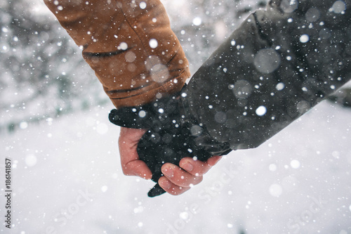 Happy Young Couple in Winter . Family Outdoors. man and woman looking upwards and laughing. Love, fun, season and people - walking in winter park. Holding hands, close-up. photo