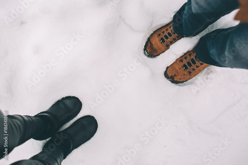 Happy Young Couple in Winter . Family Outdoors. man and woman looking upwards and laughing. Love, fun, season and people - walking in winter park. Are opposite each other, a top view, winter boots. photo