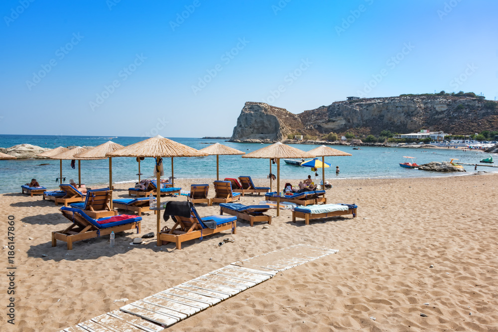 Stegna beach with sunshades and sunbeds, boats in background (RHODES, GREECE)