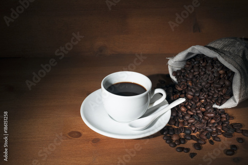 Coffee cup on wooden table with roasted beans