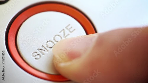 Person pushing the snooze button on an alarm clock.