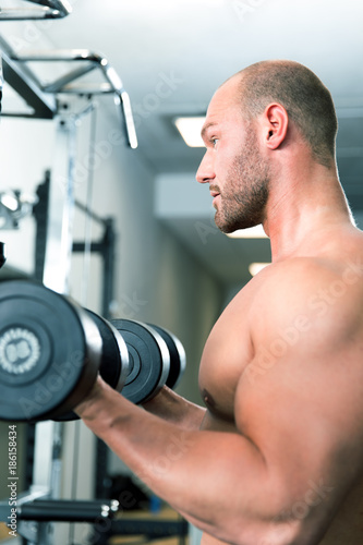 Young sexy bodybuilder man is doing his fitnes workout in the gym. pushup, biceps curls. pull ups with dumbbels © Merpics