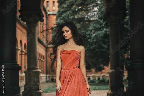 Beautiful brunette girl, with very long hair, in an orange, vintage dress © kharchenkoirina