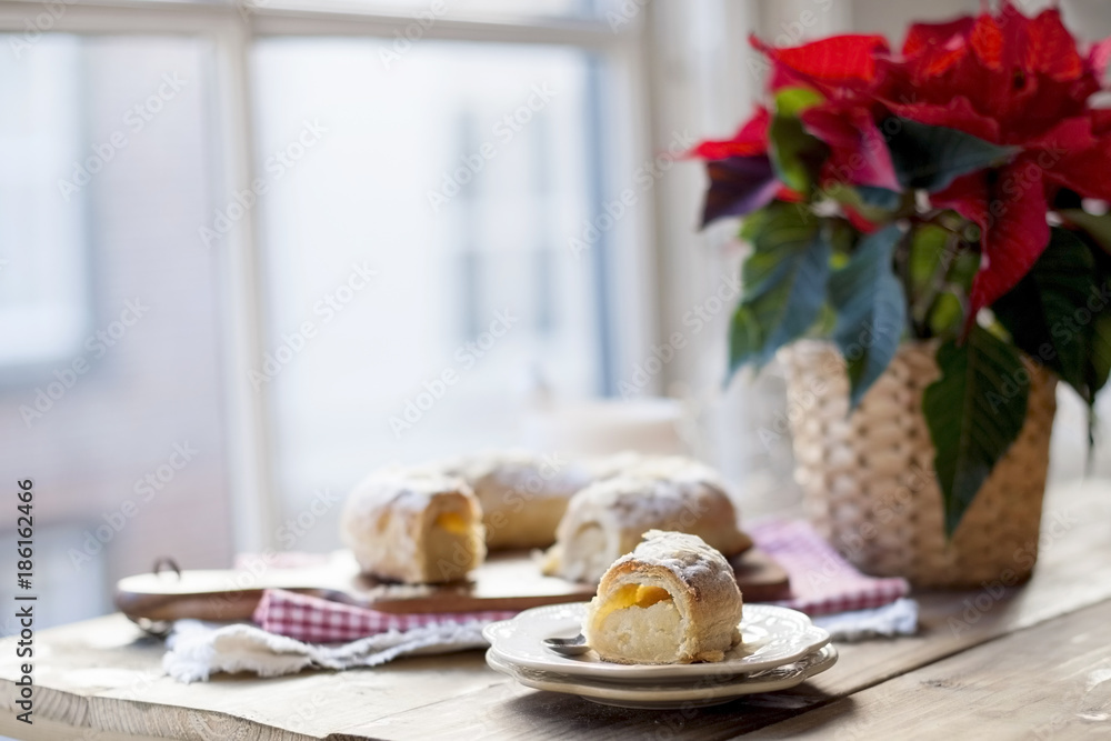 Christmas baked goods on a table near a window and a flower with red leaves
