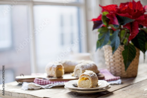 Christmas baked goods on a table near a window and a flower with red leaves